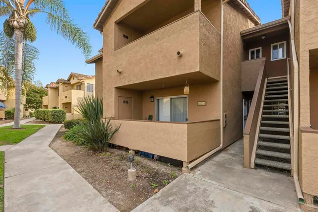 a view of a white house with a small yard plants and large tree