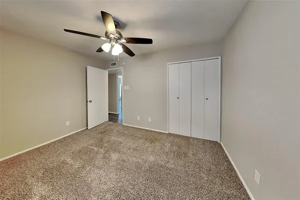 a view of an empty room and chandelier fan