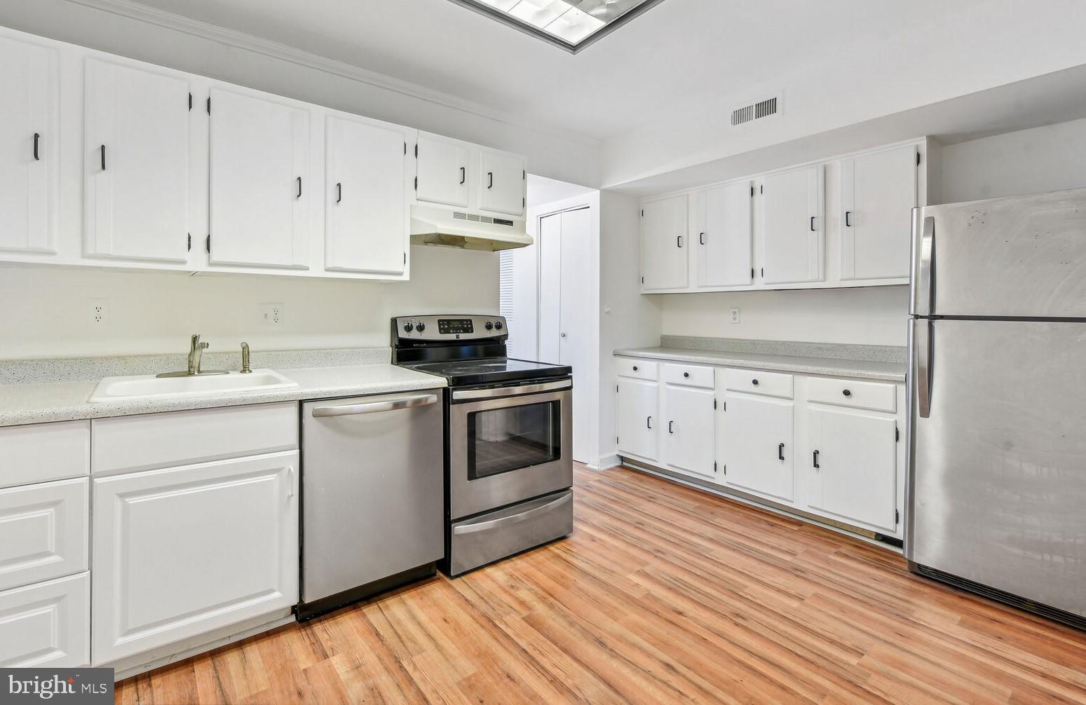 a kitchen with white cabinets white stainless steel appliances and sink