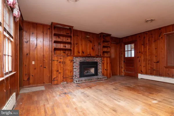 a view of an empty room with wooden floor fireplace and a window
