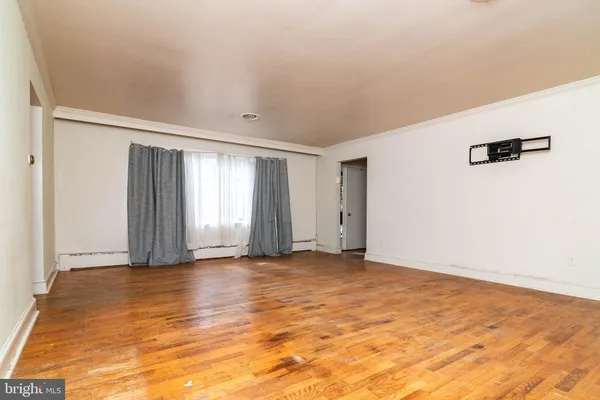 a view of an empty room with window and wooden floor