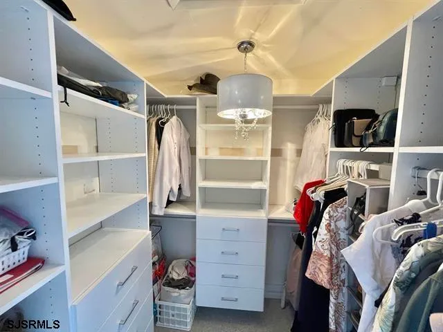 a view of walk in closet with clothes and shoes