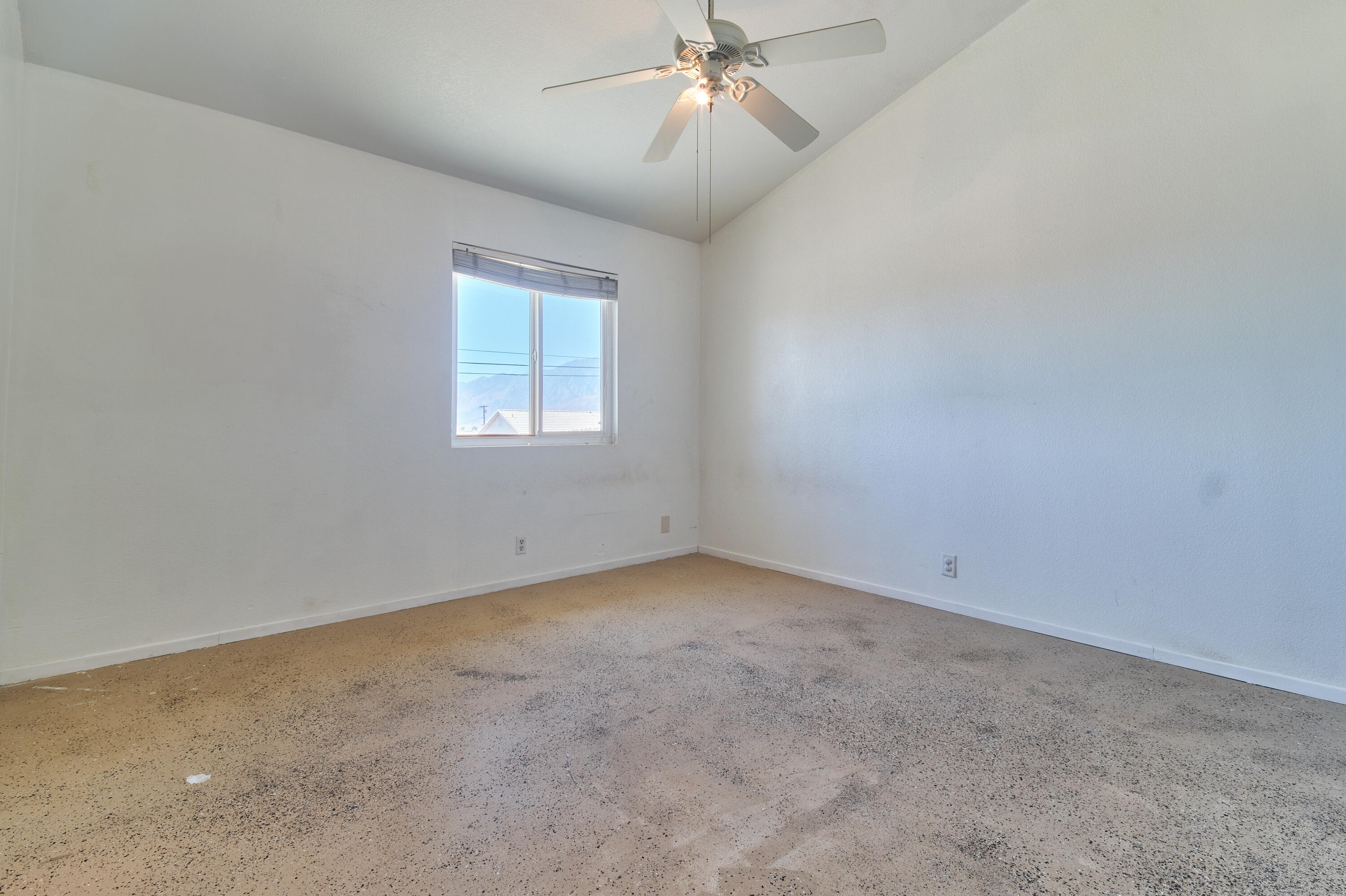 66097 San Jose Road Desert Hot Springs, CA 92240 - Photo 18 of 26 an empty room with a chandelier fan and windows