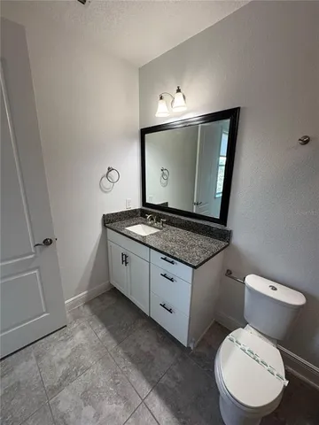 a bathroom with a granite countertop toilet sink and mirror