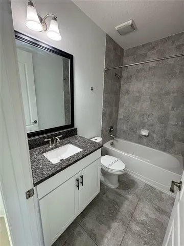 a bathroom with a granite countertop sink toilet a mirror and bathtub