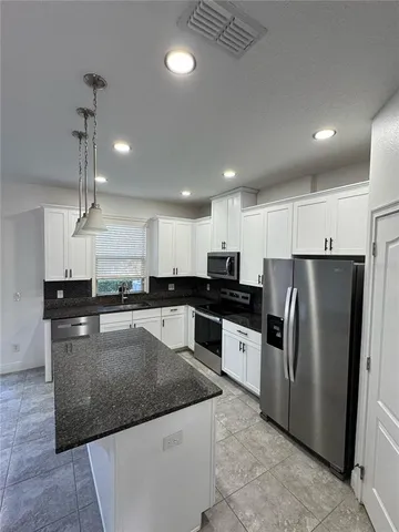 a large kitchen with a center island a counter space stainless steel appliances and cabinets