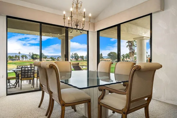 a view of a dining room with furniture a chandelier and large windows