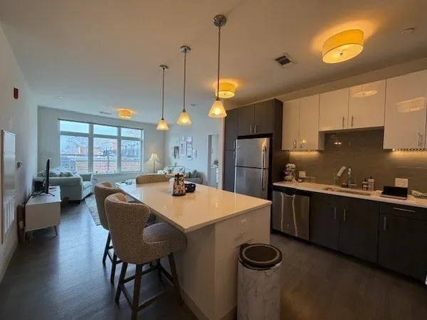 a kitchen with granite countertop a sink a stove and chairs