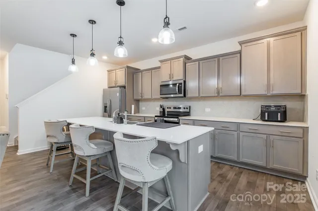 a kitchen with kitchen island granite countertop a sink a center island and appliances