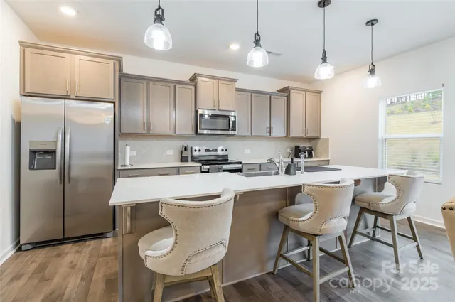 a kitchen with stainless steel appliances a dining table chairs refrigerator and sink