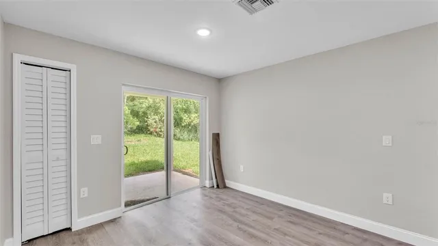 a view of an empty room with wooden floor and a window