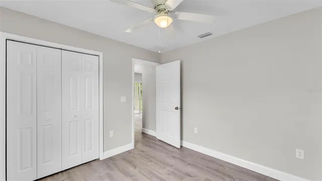 an empty room with wooden floor and fan