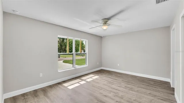 a view of empty room with wooden floor and fan