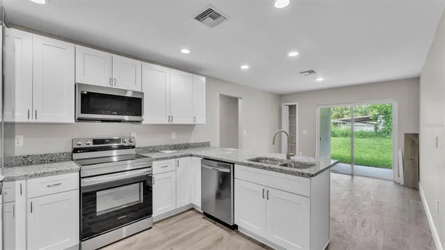 a kitchen with granite countertop a stove a sink and a microwave