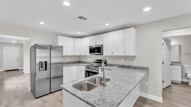 a kitchen with stainless steel appliances granite countertop a sink a stove and a refrigerator