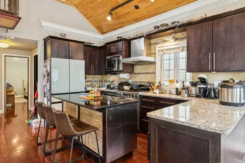 a kitchen with granite countertop kitchen island stainless steel appliances a stove a sink a refrigerator and cabinets