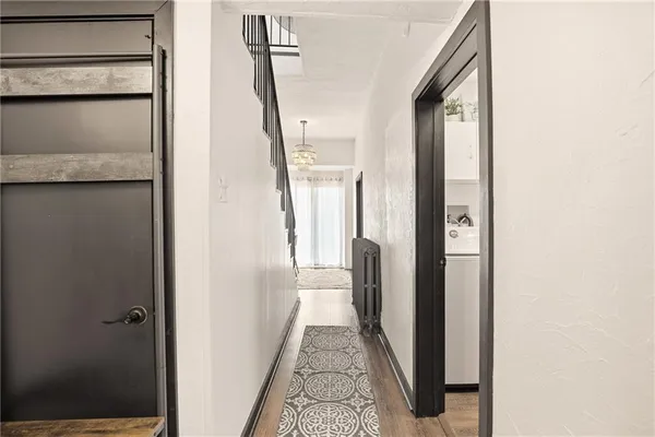 a view of a hallway with wooden floor and a bathroom