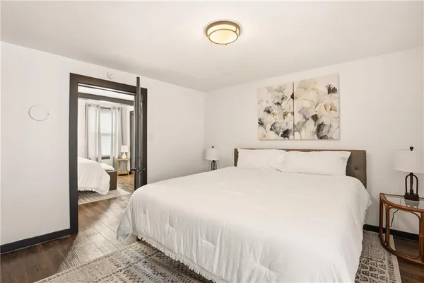 a bedroom with a bed wooden floor and window