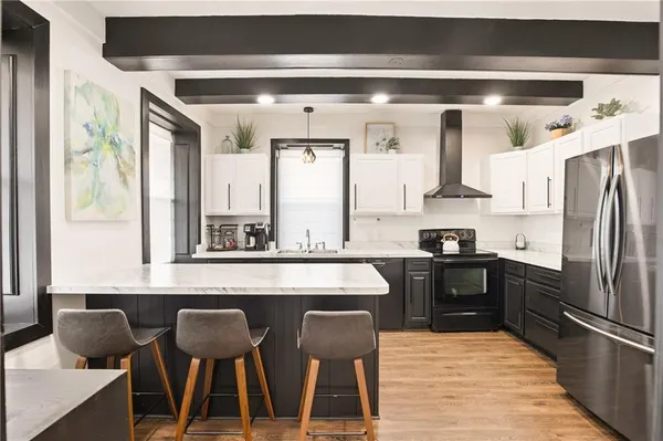 a kitchen with stainless steel appliances granite countertop a table chairs in it and wooden floors