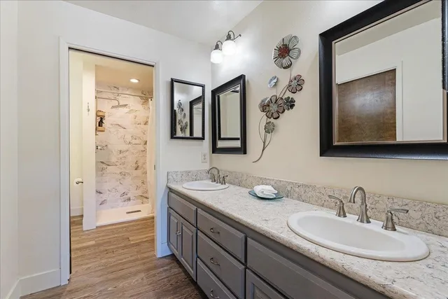 a bathroom with a granite countertop sink a mirror a vanity and a shower