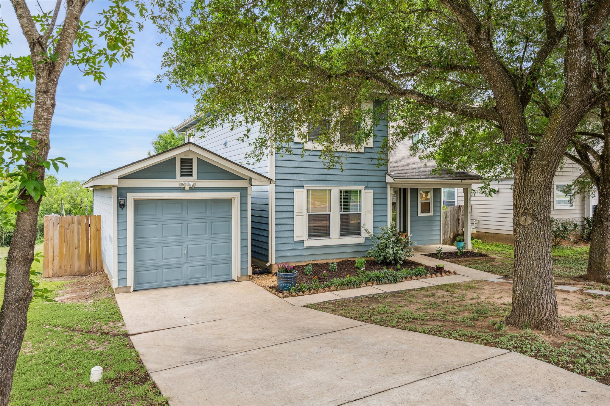 View of front facade with concrete driveway, an attached garage, and fence