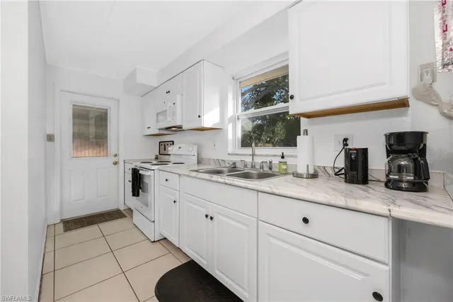 a kitchen with granite countertop white cabinets and white appliances