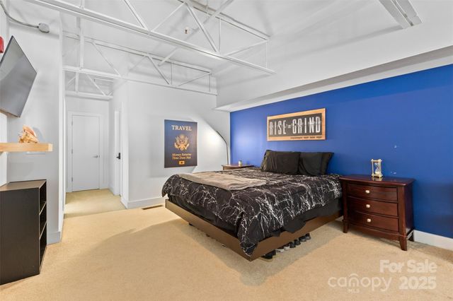 a spacious bedroom with a bed and a flat screen tv