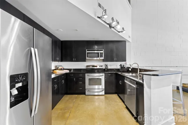 a kitchen with stainless steel appliances granite countertop a stove a sink and a refrigerator