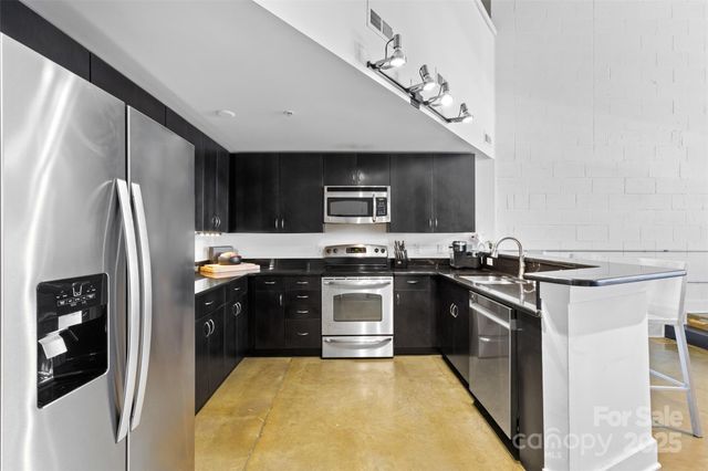 a kitchen with stainless steel appliances granite countertop a stove a sink and a refrigerator