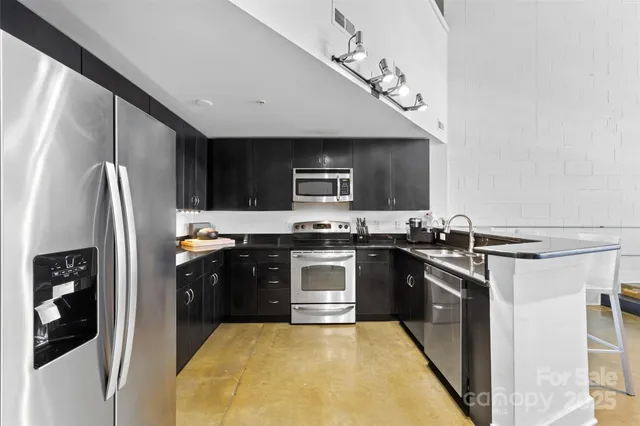 a kitchen with stainless steel appliances granite countertop a stove a sink and a refrigerator
