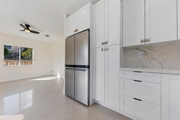 a kitchen with white cabinets and refrigerator