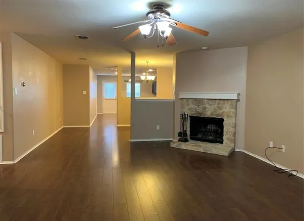 an empty room with wooden floor fire place and windows