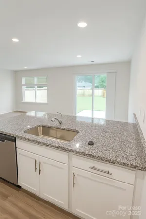a kitchen with granite countertop white cabinets and a window