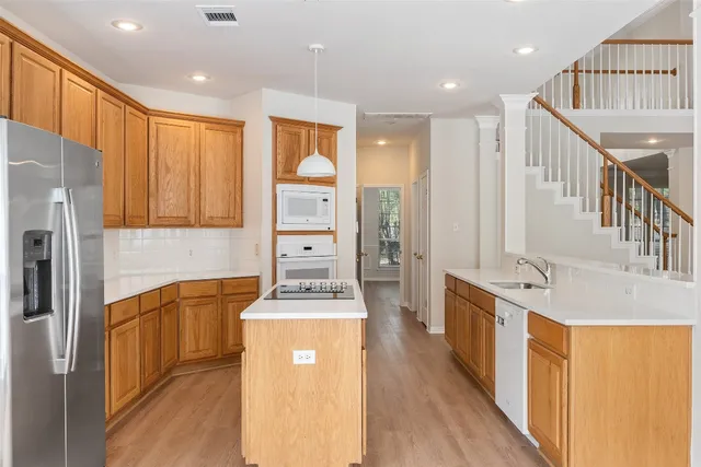 a kitchen with stainless steel appliances granite countertop a refrigerator a stove and a wooden floors