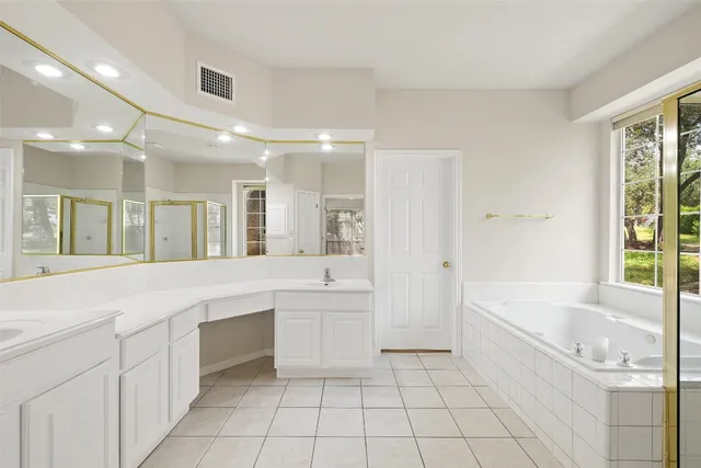 a large white bathroom with a large tub sink vanity and granite