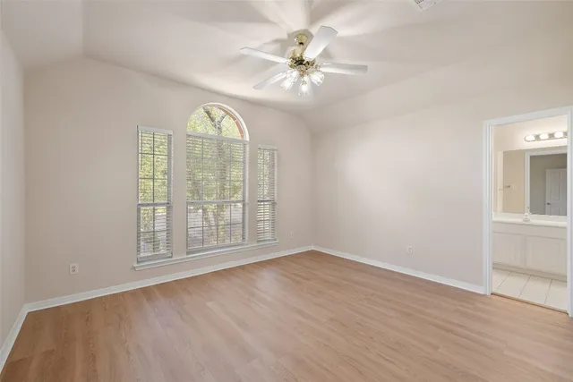 an empty room with wooden floor fan and windows