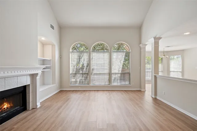 a view of an empty room with wooden floor fireplace and a window