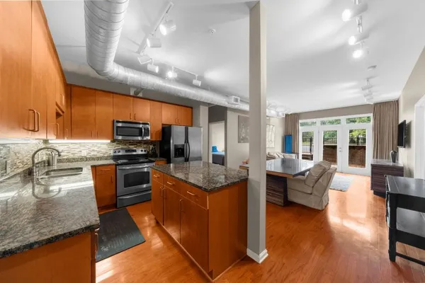 a kitchen with stainless steel appliances granite countertop a sink dishwasher stove and refrigerator with wooden floor