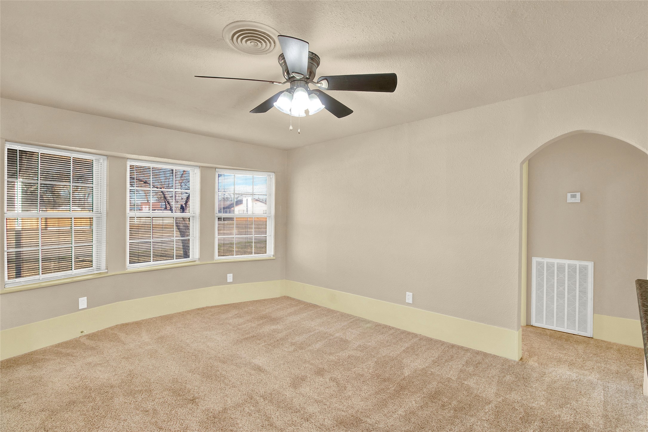 506 Edgebrook Drive Houston, TX 77034 - Photo 2 of 18 This spacious room features neutral walls, a ceiling fan, and ample natural light from large windows. The carpeted floor adds warmth, while the arched doorways provide a charming architectural detail.