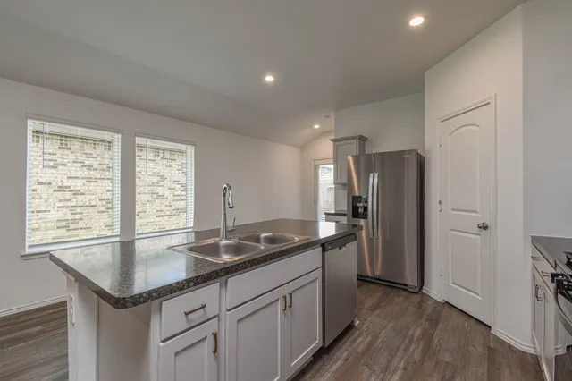 a kitchen with stainless steel appliances granite countertop a sink a stove and a refrigerator