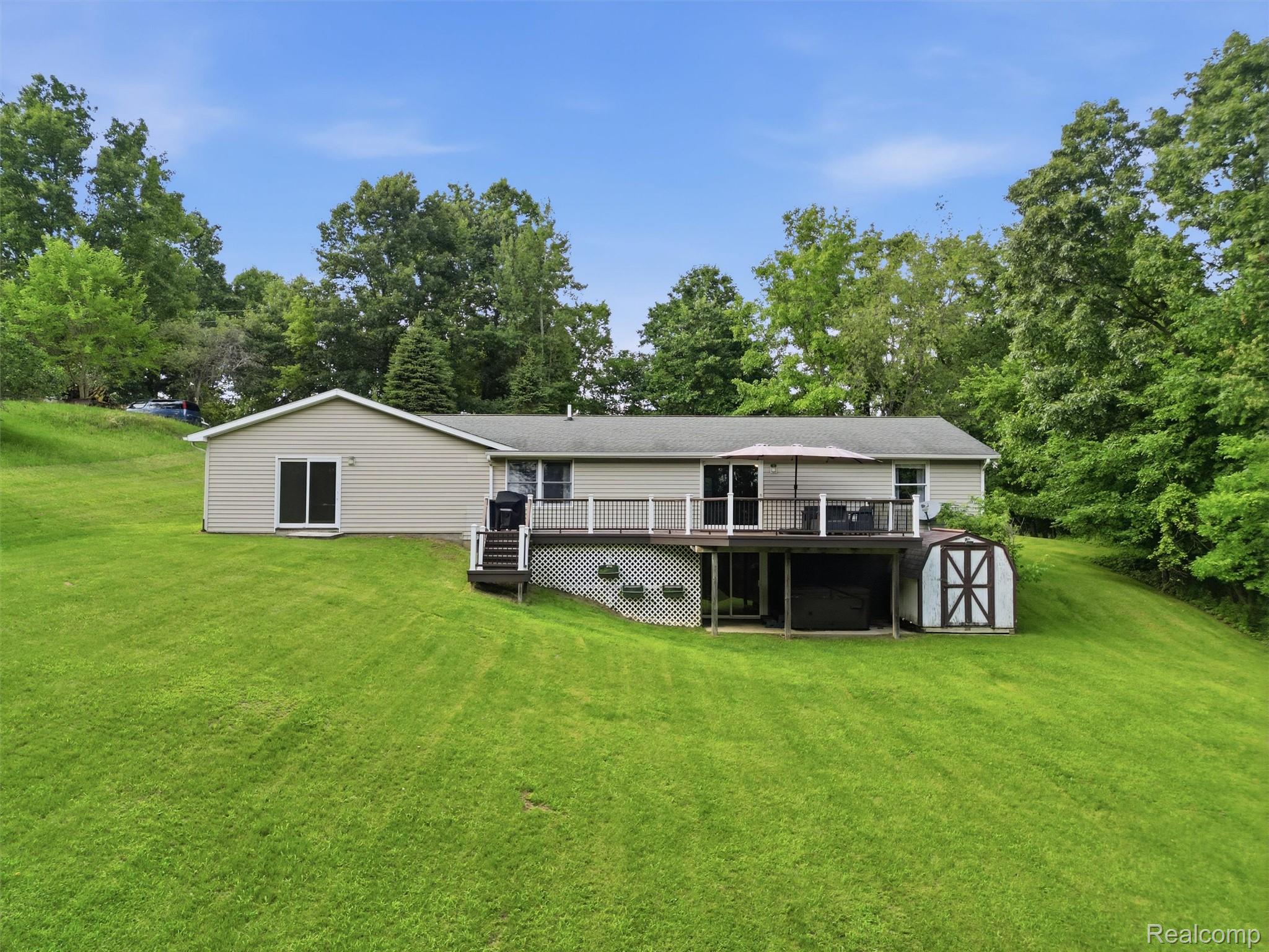 5003 Mason Road Howell, MI 48843 - Photo 51 of 59 Ranch-style residence featuring a spacious rear deck, full-light sliding glass doors, a lower-level patio, and a storage shed