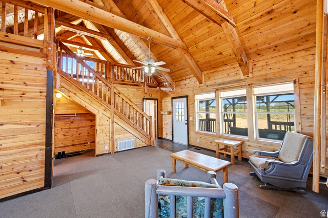 10937 South County Road, Unit 29 Duchesne, UT 84021 - Photo 3 of 41 Spacious living area featuring extensive natural wood plank walls and ceilings, exposed wood beams, and a prominent wooden staircase leading to an upper level