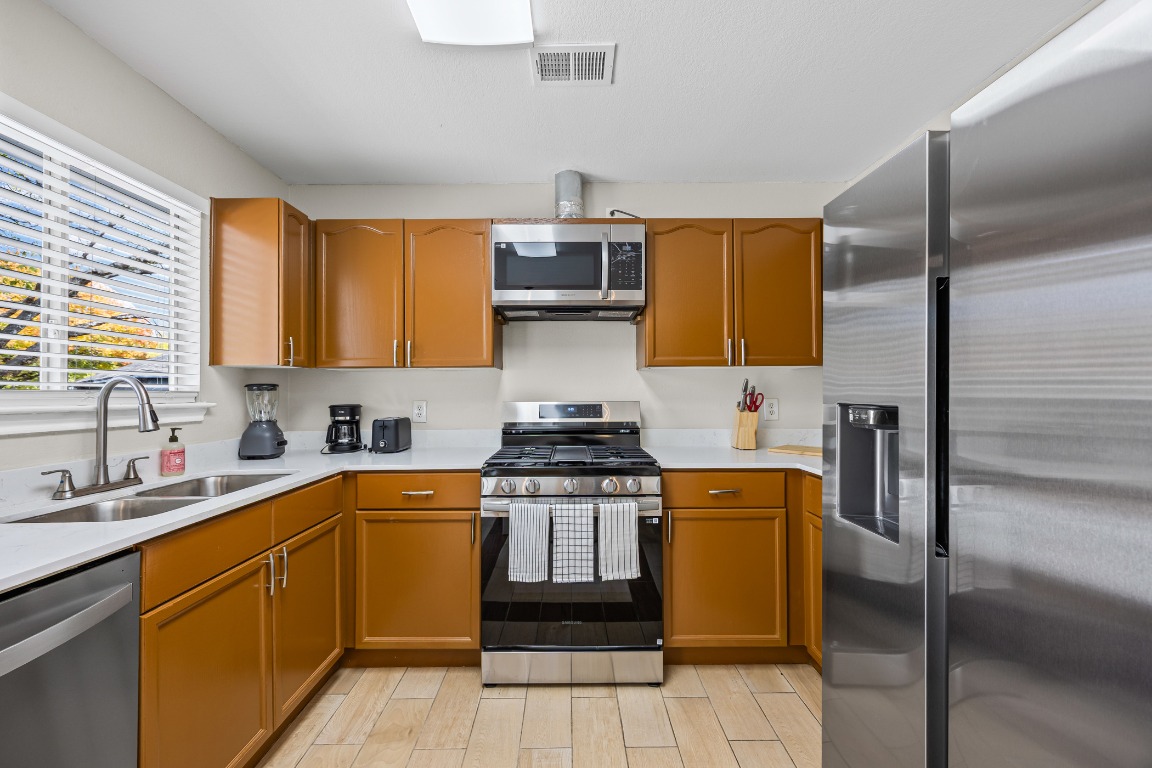 5006 Acorn Grove Court Austin, TX 78744 - Photo 11 of 36 a kitchen with stainless steel appliances granite countertop a stove a sink and a refrigerator