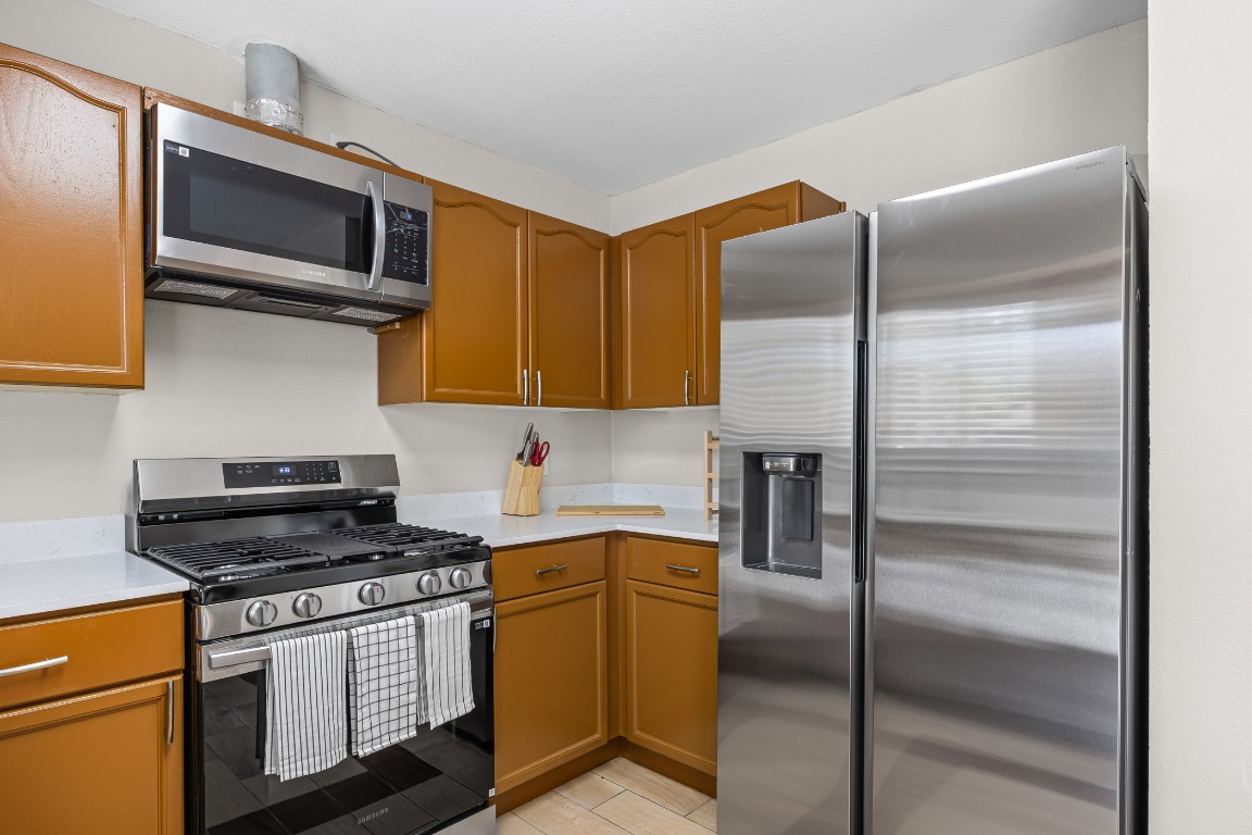 5006 Acorn Grove Court Austin, TX 78744 - Photo 12 of 36 a kitchen with a refrigerator stove and microwave