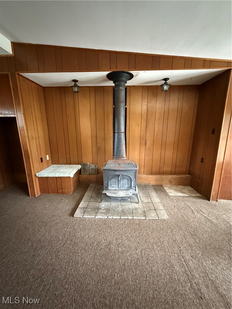3122 South Medina Line Road Wadsworth, OH 44281 - Photo 40 of 41 Room details with a wood stove, wood walls, and carpet floors