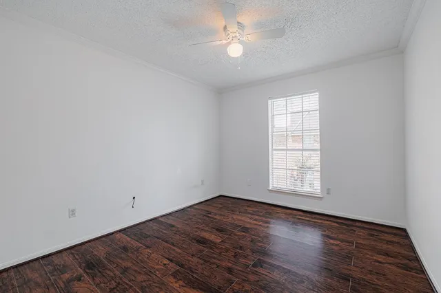 an empty room with wooden floor ceiling fan and windows