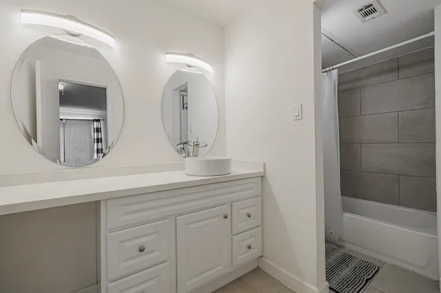 a bathroom with a double vanity sink mirror and bathtub