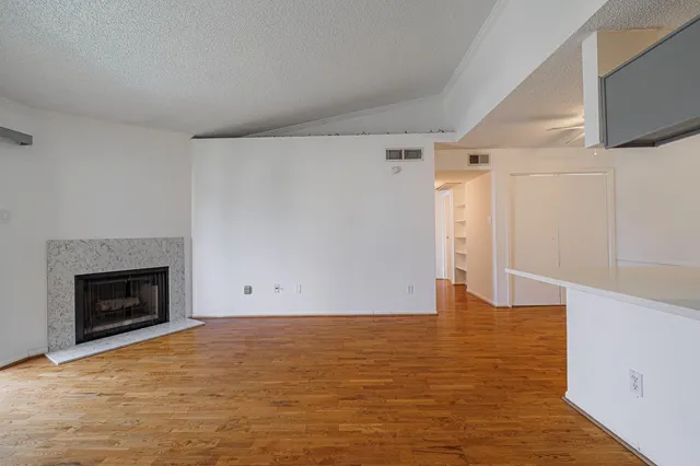 a view of empty room with wooden floor and fireplace