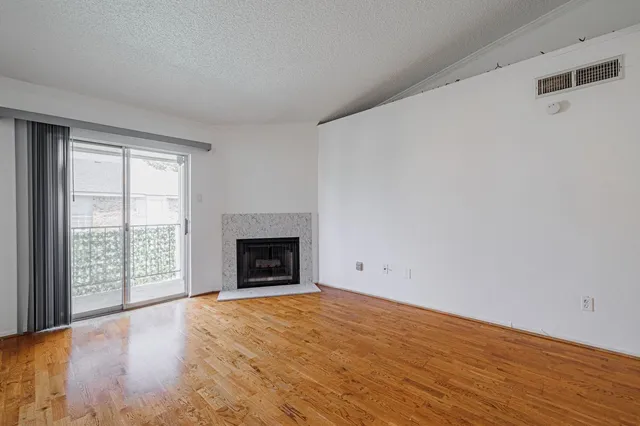 a view of empty room with wooden floor and fireplace