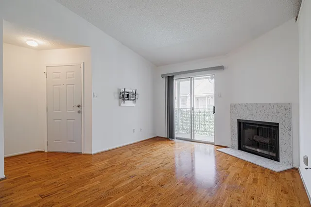 an empty room with wooden floor fireplace and windows